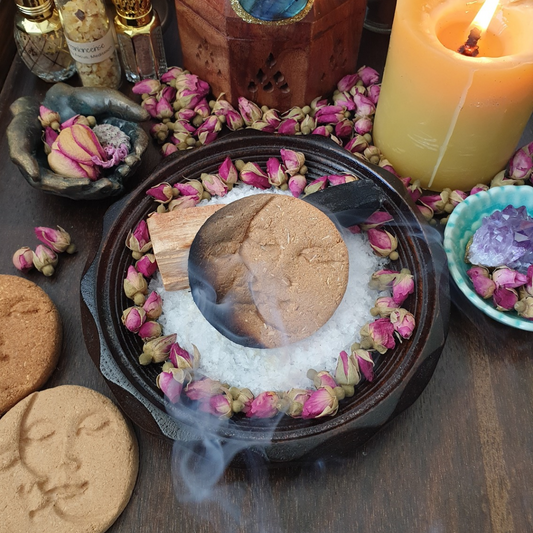 Sandalwood and Lemongrass Incense Disc, Sun and moon design on a plate of salt with a palo santo stick and pink rose buds.